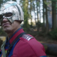 John Cena as Peacemaker, smirking and standing in a forest, in HBO Max's Peacemaker.